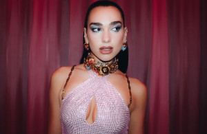 Dua Lipa poses next to a car, wearing a micro bikini with gold chains